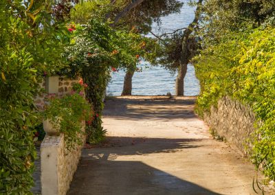 Kameni put vodi do plaže u Petrčanima, Zadar, Dalmacija. Put je ukrašen cvijećem i drvećem i vodi do male plaže. Plaža je popularno mjesto za kupanje i sunčanje, a nalazi se samo minutu hodanja od kuće.